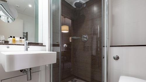 a bathroom with a shower, sink, and mirror at Grand Jersey Hotel and Spa in Saint Helier Jersey