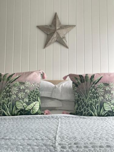 a bed with two pillows and a star on the wall at Westward 14 Polzeath in Polzeath