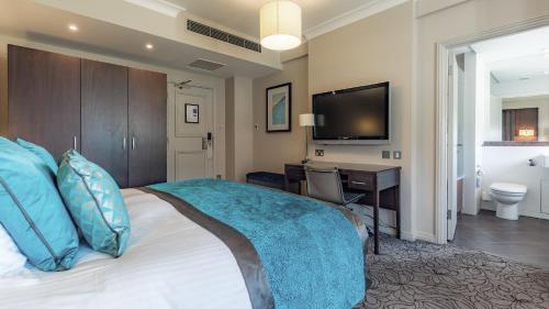 a bedroom with a bed with a desk and a television at Grand Jersey Hotel and Spa in Saint Helier Jersey