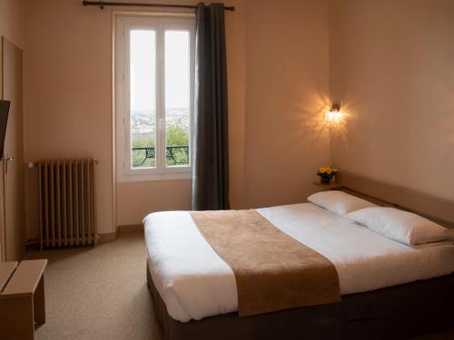 Un dormitorio con una cama grande y una ventana en Hôtel des Pyrénées en Angoulême