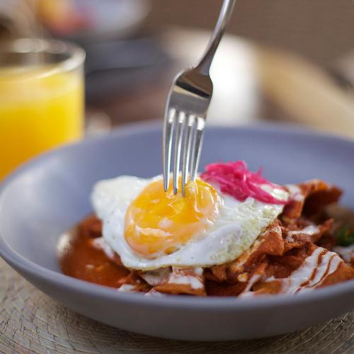 um prato de comida com um ovo frito e bacon em Hotel Amatte San Miguel de Allende em San Miguel de Allende