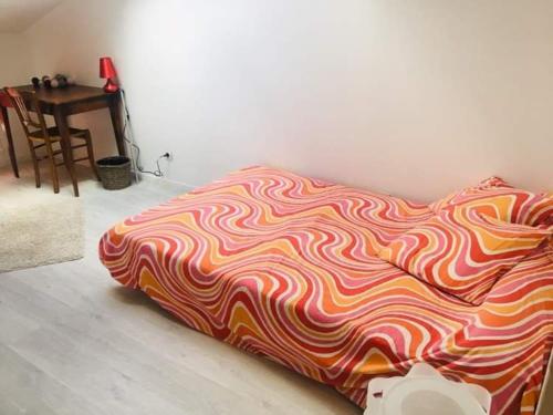 ein Bett mit einer bunten Decke auf dem Boden neben einem Tisch in der Unterkunft Maison in Dompierre-les-Ormes