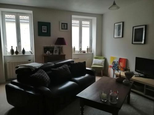 ein Wohnzimmer mit einem schwarzen Ledersofa und einem Tisch in der Unterkunft Maison in Dompierre-les-Ormes