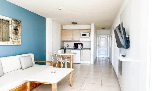 a living room with a white couch and a kitchen at Playa Del Sol - Adults Only in Playa del Ingles