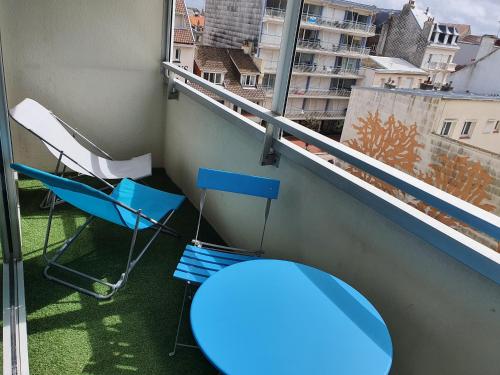 d'un balcon avec une table bleue, des chaises et une fenêtre. dans l'établissement OASIS du TOUQUET, à Le Touquet-Paris-Plage