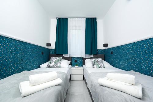 two twin beds in a room with blue walls at Apartamenty Prestige in Łeba