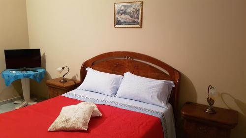 una camera da letto con un letto con una coperta rossa e cuscini bianchi di Le Bistrot a Ficarazzi