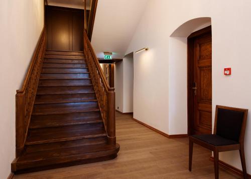 a hallway with a wooden staircase and a chair at Schloss Fellin Boutique Hotel and Spa in Viljandi