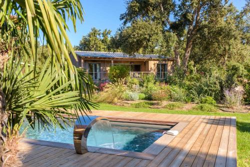 a swimming pool with a wooden deck and a house at Version Lodge in Porto-Vecchio