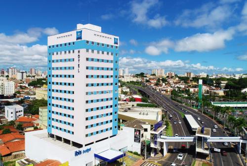 a tall white building in front of a city at Íbis Budget Uberlândia in Uberlândia