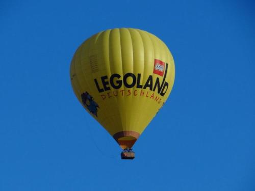 a yellow hot air balloon flying in the sky at Ferienwohnung Maria Waldblick 95 qm, in Burtenbach