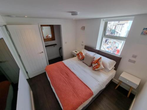 a small bedroom with a bed and two windows at Chy Mor Apartment 1 in St Ives