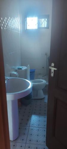 a white bathroom with a toilet and a sink at IS Guest House in Cape Coast
