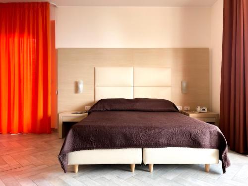 a bedroom with a large bed and red curtains at Taormina Hotel Calipso in Mazzeo