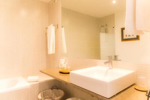 uma casa de banho branca com um lavatório e um espelho em Cercas Velhas em Sagres