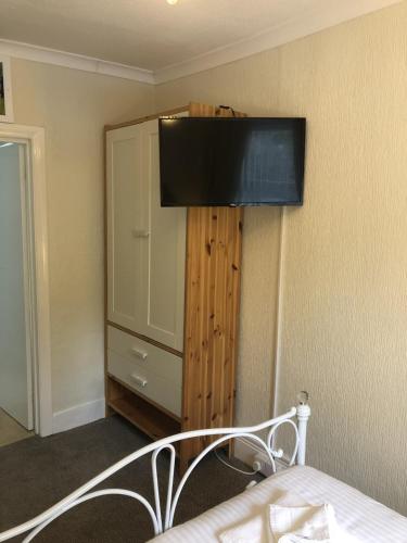 a bedroom with a bed with a television on the wall at The Purple Tree Guest House in Torquay