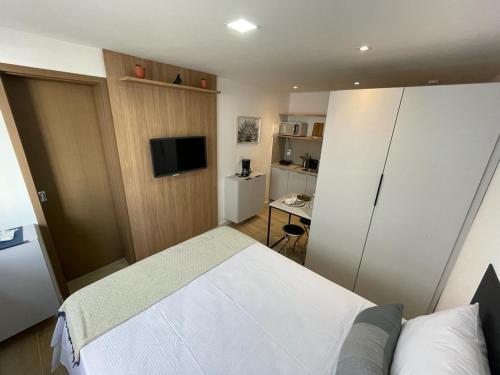 um quarto com uma cama e uma televisão em Bauten Cabo Branco - Flat uma quadra da praia em João Pessoa