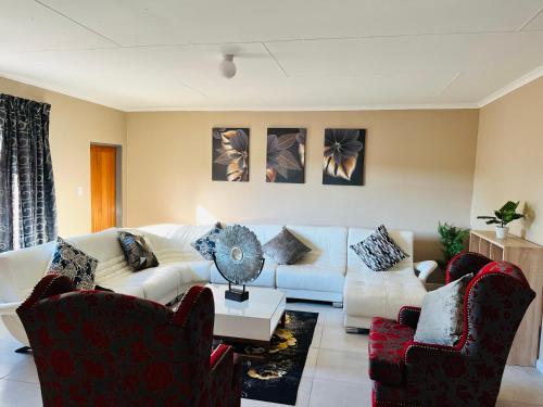 a living room with a white couch and two chairs at Aaron's Nest Bed and Breakfast in Ladysmith