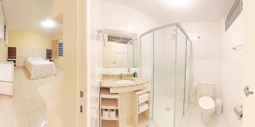 een witte badkamer met een wastafel en een douche bij Hotel Curitiba Campo Comprido in Curitiba