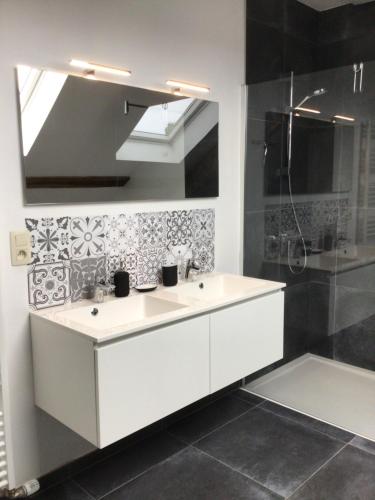 een badkamer met een witte wastafel en een douche bij Le grenier de Charlotte in Libin