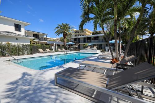 uma piscina com palmeiras junto a um edifício em Tropic Isle Beach Resort em Deerfield Beach