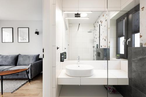 een witte badkamer met een wastafel en een douche bij Komfortowe OH Apartamenty Zator in Zator