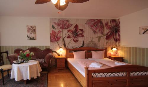 a bedroom with a bed and a table with flowers on the wall at Kreuzerhof Hotel Garni in Rothenburg ob der Tauber