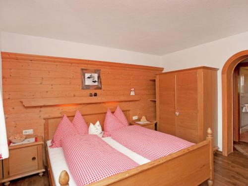 Schlafzimmer mit einem Bett mit roten und weißen Kissen in der Unterkunft Apartment near Zillertal ski area in Rohrberg