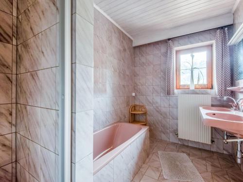 y baño con bañera rosa y lavamanos. en Modern vacation apartment with a view, en Hainzenberg