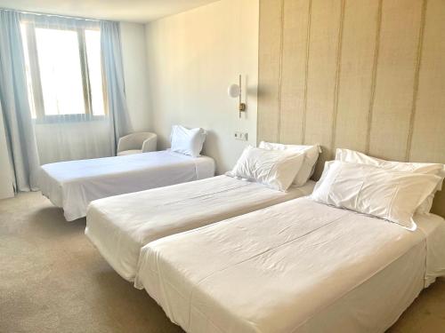two beds in a hotel room with white sheets and pillows at Hotel Oriente in Zaragoza