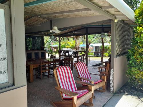 a patio with wooden chairs and a table and tables at Hotel El Colibri Rojo - Cabinas - Le Colibri Rouge in Cahuita