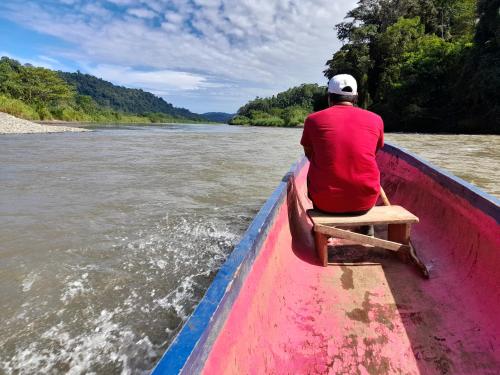 a man sitting in a boat on a river at Hotel El Colibri Rojo - Cabinas - Le Colibri Rouge in Cahuita