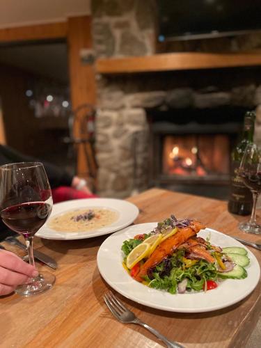 a table with a plate of food and a glass of wine at Pourvoirie du Lac Blanc in Saint-Alexis-des-Monts