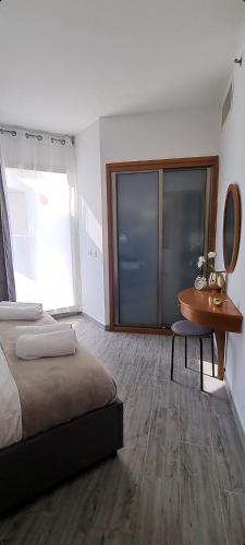 a bedroom with a bed and a table and a mirror at GO to apartments in Leonardo in Bat Yam