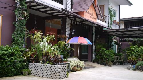 a patio with an umbrella and plants in front of a building at Baan Jaru in Chiang Rai