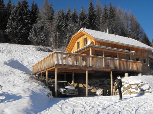 a man standing in the snow in front of a log cabin at Chalet in Styria near the ski area in Stadl an der Mur