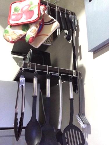 a bunch of utensils hanging from a rack in a kitchen at Beach condos at Pico de Loro Cove - Wi-Fi & Netflix, 42-50''TVs with Cignal cable, Uratex beds & pillows, equipped kitchen, balcony, parking - guest registration fee is not included in Nasugbu