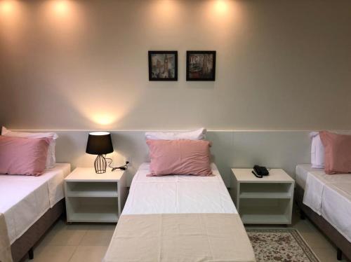 a room with two beds with pink pillows and tables at Baruch Hotel in Araguaína