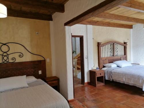 a bedroom with two beds and a mirror at Hotel Na´Lum in San Cristóbal de Las Casas