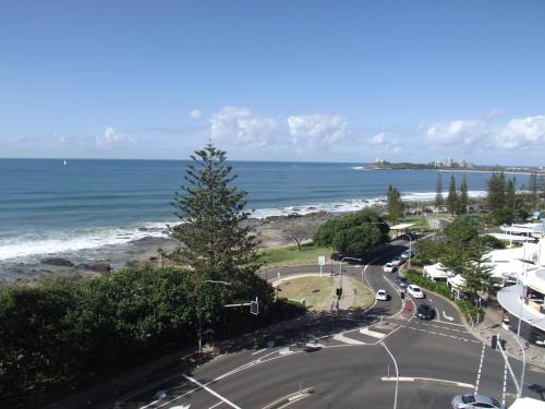 a road next to the ocean with a tree at Northwind Beachfront Apartments in Mooloolaba