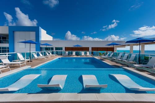 uma piscina com cadeiras e guarda-sóis num edifício em Aquamare Hotel em San Andrés