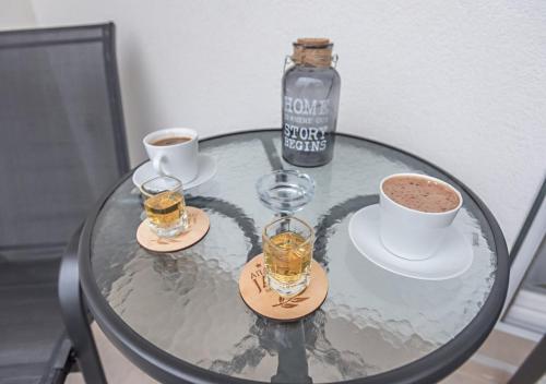 a glass table with three glasses and a bottle on it at Apartman Kesten - Апартман Кестен in Banja Koviljača