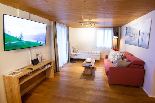 a living room with a red couch and a flat screen tv at Apartments Chalet Wirz Travel in Sarnen