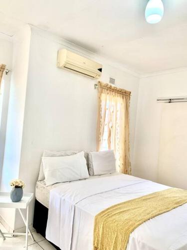 a bedroom with a bed with white sheets and a window at Awesome Sea views! House near Zimbali in Densainagar