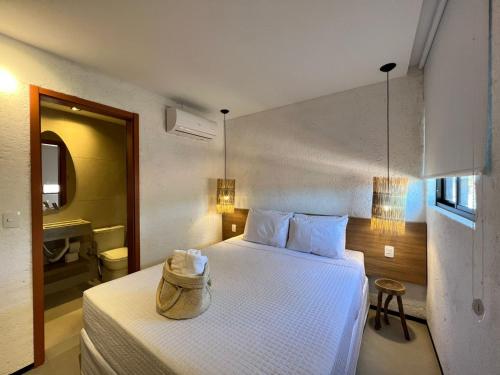 a bedroom with a white bed with a hat on it at PATACHO VILLE - Rota Ecológica dos MILAGRES in Pôrto de Pedras