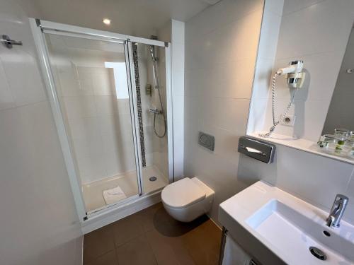 a bathroom with a shower and a toilet and a sink at Holiday Inn Paris-Auteuil by IHG in Paris