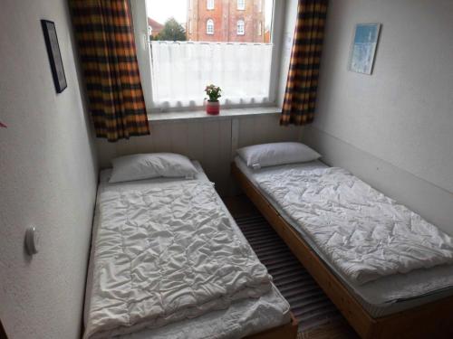 Duas camas num pequeno quarto com uma janela em Fewo 91 WHG B 15 in Burhave em Burhave