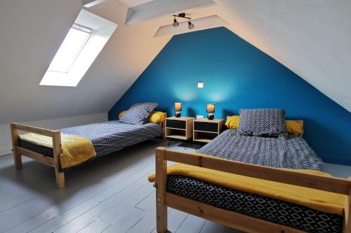 ein Schlafzimmer im Dachgeschoss mit 2 Betten und einer blauen Wand in der Unterkunft Ti ker 2 SPA in Plourin