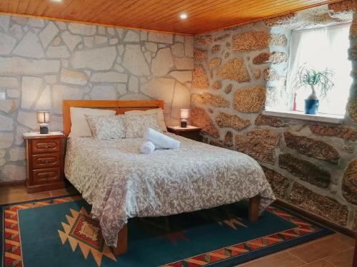een slaapkamer met een bed en een stenen muur bij Casa do Penedo in Viana do Castelo