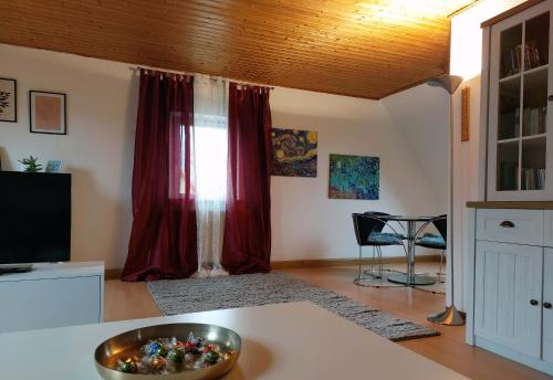 ein Wohnzimmer mit roten Vorhängen und einer Schüssel auf einem Tisch in der Unterkunft Ferienwohnung am Salzsee in Bad Windsheim